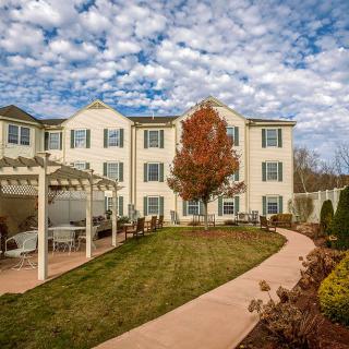A charming residential building with a well-maintained garden and pathway under a cloudy autumn sky.