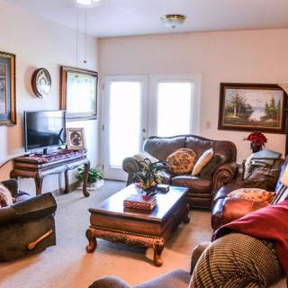 A cozy living room with comfortable sofas, a television, and decorative paintings on the walls.