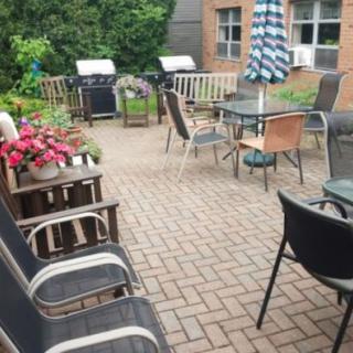 A cozy outdoor patio with seating, tables, an umbrella, and a garden view.