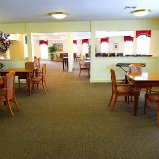 A spacious dining area with neatly arranged tables and chairs, illuminated by soft overhead lights.