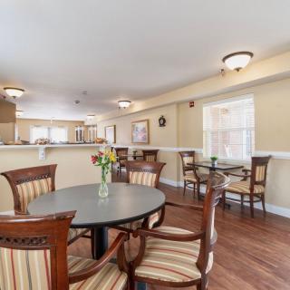 A cozy dining space with wooden chairs and tables, complemented by soft lighting and wood flooring.