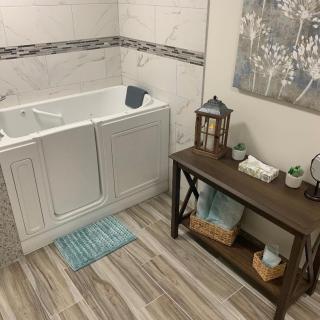 A well-decorated bathroom featuring a walk-in bathtub, wooden floors, and stylish decor.