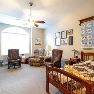 A cozy bedroom with a bed, two chairs, and various decorations on the walls.