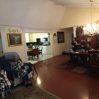 A cozy living and dining area with a chandelier, featuring a glimpse into the kitchen.