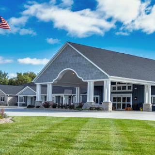 A modern architectural building set against a bright blue sky, featuring manicured lawns and an American flag.