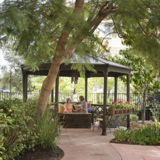 A peaceful gazebo in a lush garden setting with people relaxing inside.