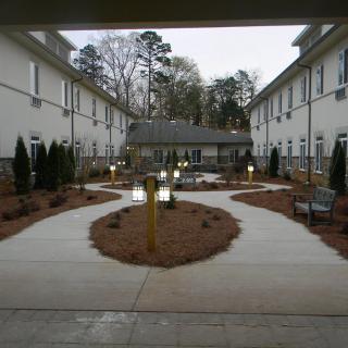 A well-maintained courtyard with paved pathways and greenery between two buildings.