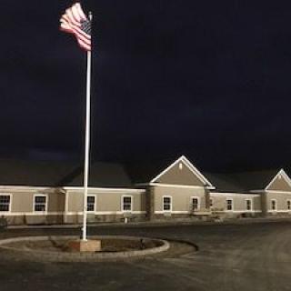 A building with an American flag flying at night, illuminated by lights.