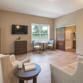 A cozy and modern living room featuring comfortable seating, a television, and a dining area bathed in natural light.