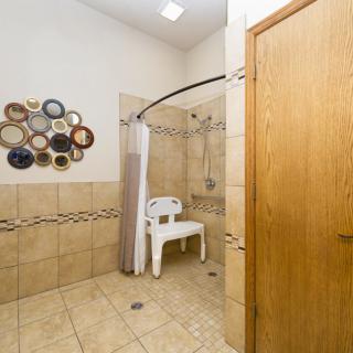 An accessible bathroom featuring a shower with a chair and decorative wall accents.