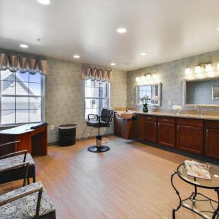 A well-lit salon interior with a barber chair, mirrors, and wooden cabinets.