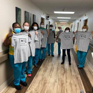A dedicated team of healthcare workers proudly displaying their new t-shirts in the hospital corridor.