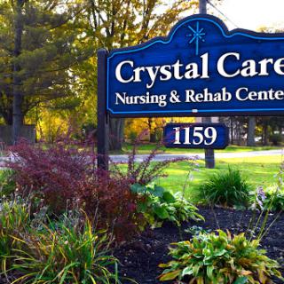The entrance sign of Crystal Care Nursing & Rehab Center surrounded by vibrant landscaping.