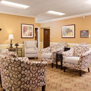 A cozy living room with patterned chairs and framed artwork.