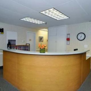 A modern reception area with a desk, flower arrangement, and wall clock.
