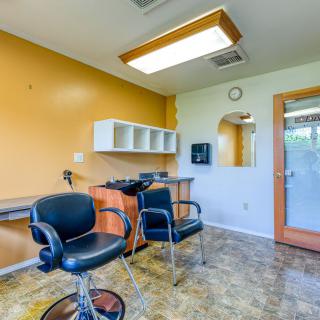 A brightly lit hair salon with chairs and a mirror.