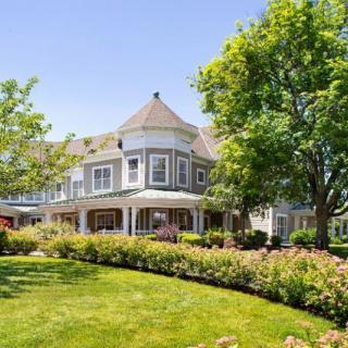 A large house with a lush garden and trees surrounding it.