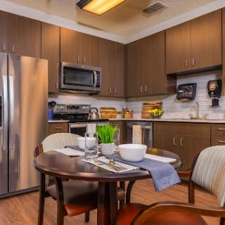 A modern kitchen featuring sleek cabinetry, stainless steel appliances, and a cozy dining setup.