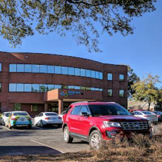 A red SUV parked in front of a modern office building on a clear day.