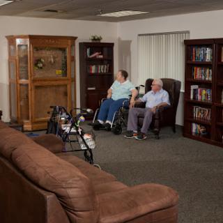 Two elderly individuals, one in a wheelchair, relax in a cozy living room setting.