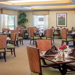 A well-appointed dining room with neatly arranged tables and chairs, featuring large windows and tasteful decor.