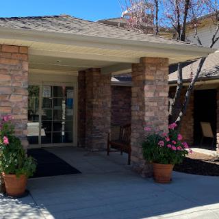 A welcoming entrance of a home featuring stone pillars and vibrant flowers.