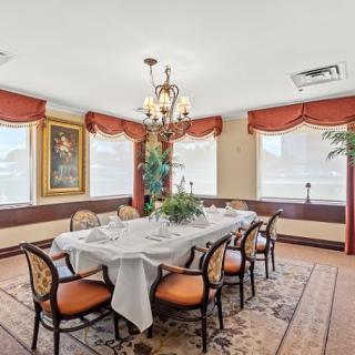 An elegantly decorated dining room with a large table set for a meal, surrounded by chairs and illuminated by a chandelier.