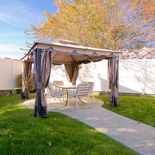 A backyard gazebo with outdoor furniture surrounded by a well-maintained lawn.