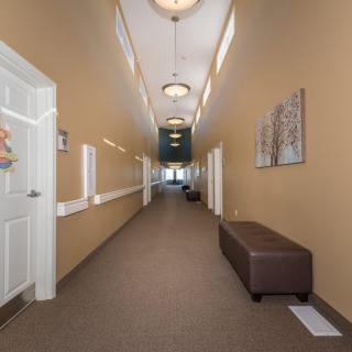 A well-lit hallway with doors on both sides and a bench along the wall.