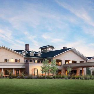 A large, elegant house with a well-maintained lawn and cloudy sky backdrop.