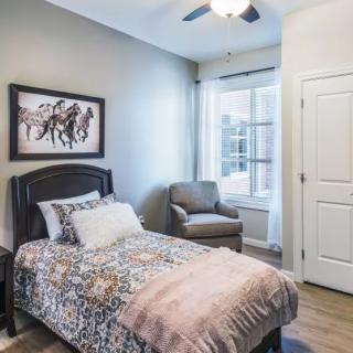 A cozy bedroom with a single bed, armchair, and large window.