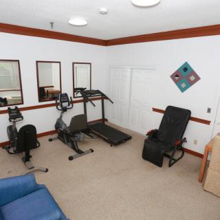 A small home gym with exercise equipment including a treadmill and stationary bike, surrounded by mirrors.