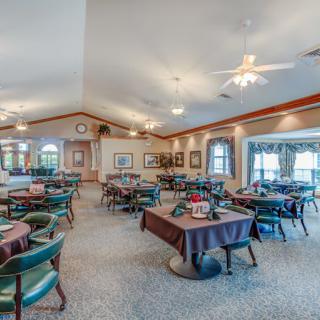 A spacious dining area with multiple tables and chairs, decorated with ceiling fans and artwork on the walls.