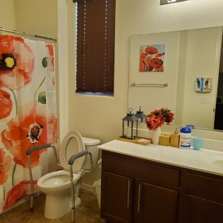 A brightly decorated bathroom featuring a floral shower curtain and a modern vanity.