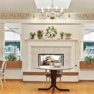 A cozy living room with an elegant fireplace, adorned with floral decorations and a classic chandelier.