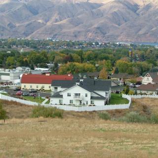 A suburban landscape with houses, a white fence, and mountains in the background.