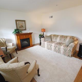A cozy living room with a sofa, chairs, a fireplace, and a carpet.