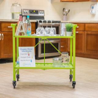 A vibrant green bar cart set up in a modern kitchen, ready for serving drinks.