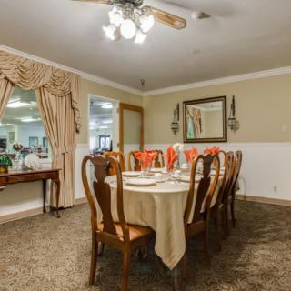 A cozy dining room with a set table, elegant chandeliers, and classic decor.