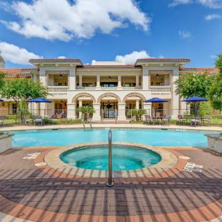 A luxurious outdoor swimming pool in front of a grand resort building under a clear blue sky.