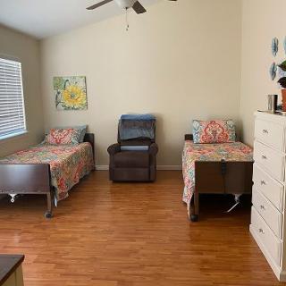 A cozy bedroom with two single beds, a wooden floor, and a comfortable chair.