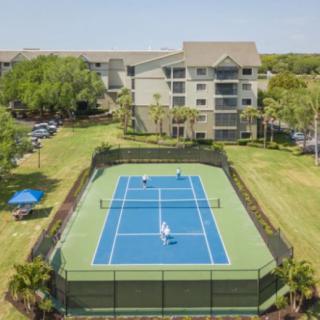 Aerial view of a tennis court situated next to a multi-story residential building.