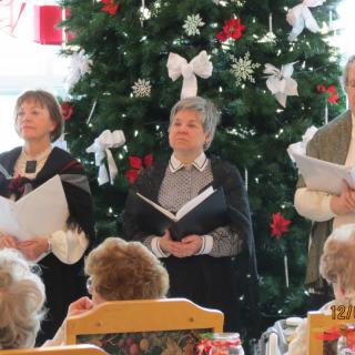 A choir performs in front of a decorated Christmas tree.