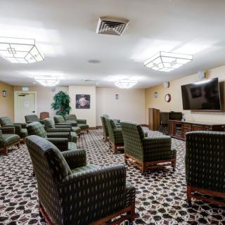 A cozy lounge area with armchairs and a television, featuring patterned carpeting and modern ceiling lighting.