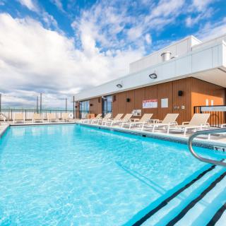 Rooftop swimming pool with lounge chairs on a sunny day.