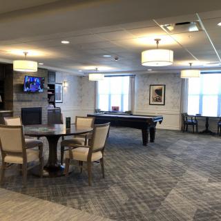 A modern lounge area featuring a pool table, seating arrangements, and a television.
