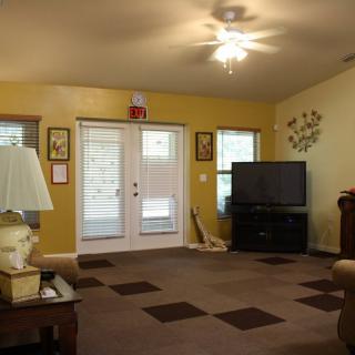 A cozy living room featuring a carpeted floor, television, and warm lighting.