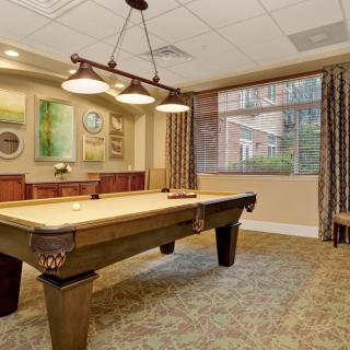 A cozy recreation room featuring a pool table, artistic decor, and warm lighting.