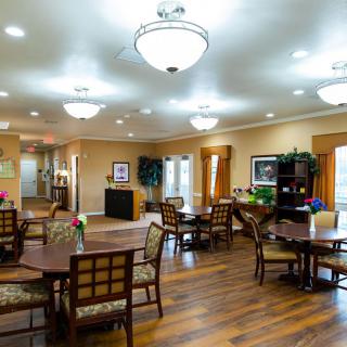 A spacious and well-lit dining area with wooden flooring and comfortable seating arrangements.
