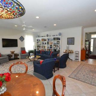 A cozy living room with a spacious seating area and a large TV, complemented by decorative bookshelves and a colorful stained glass light fixture.